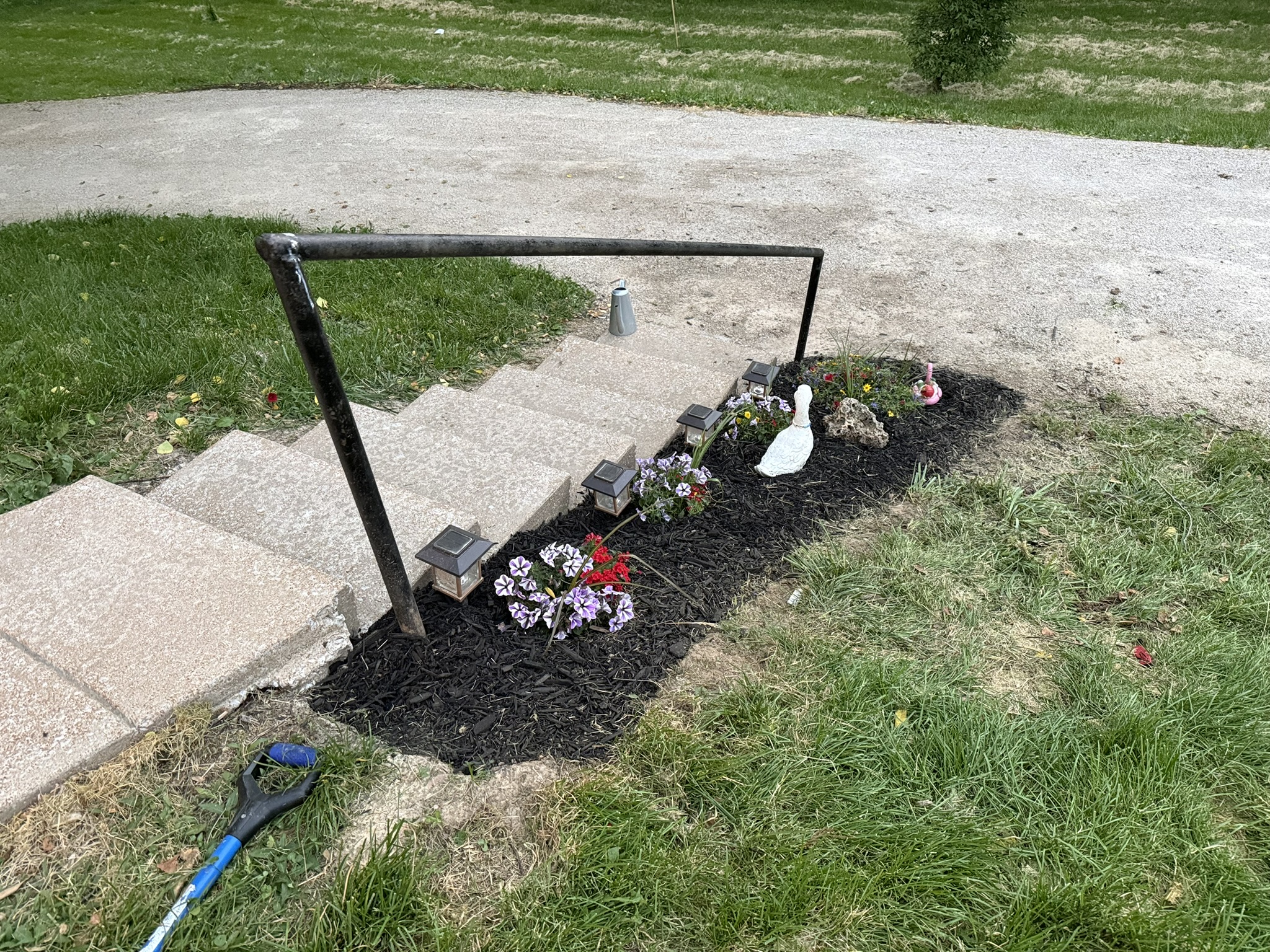 Flowers, dark mulch and path lights beside the front steps in daylight