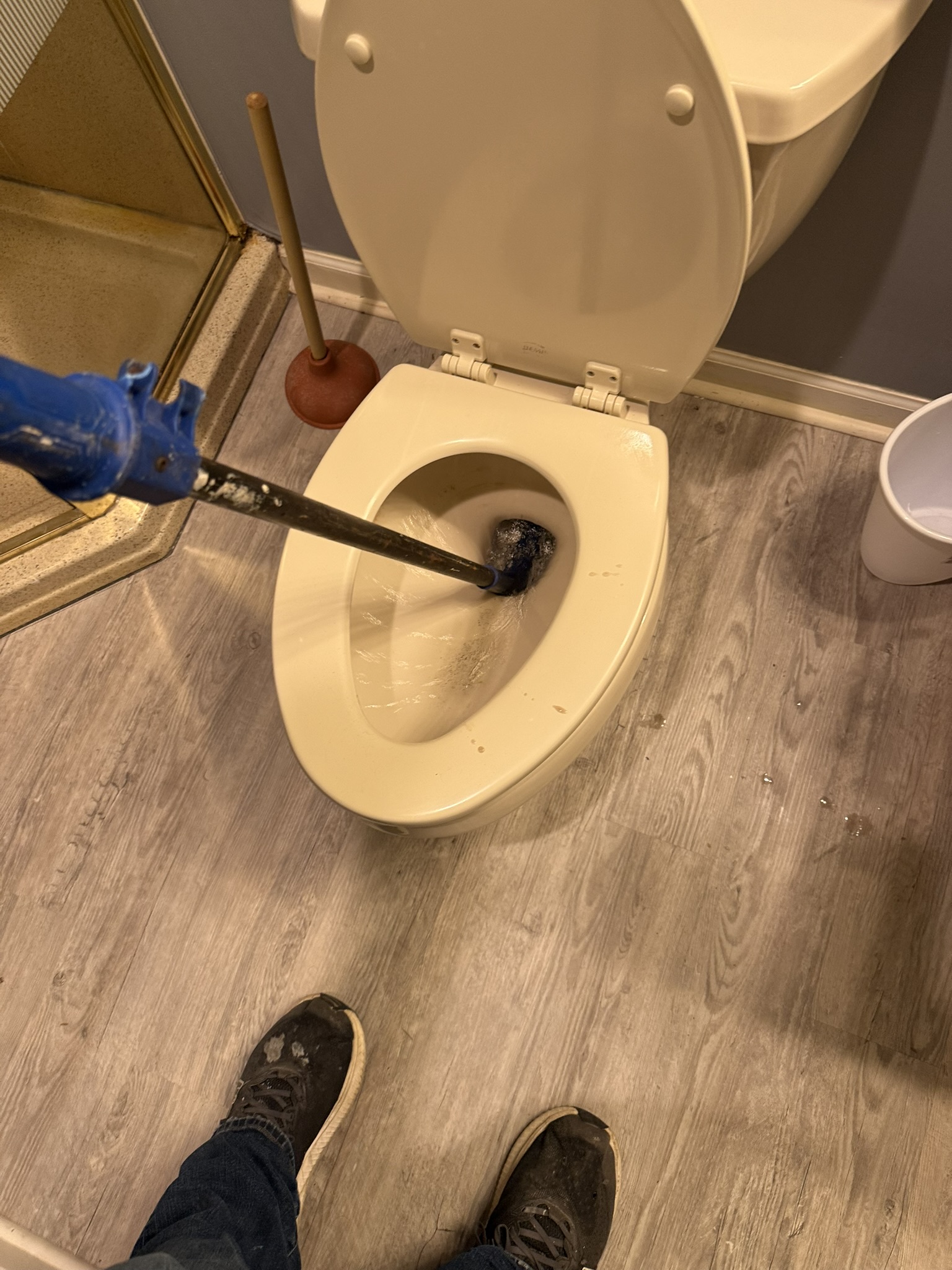 Toilet unclogging in progress with a tool in the bowl